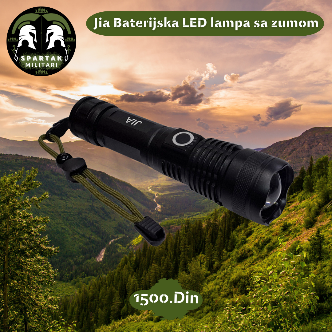 Jia LED baterijska lampa sa kaišem za ruku, položena na planinskom pejzažu pri zalasku sunca.
