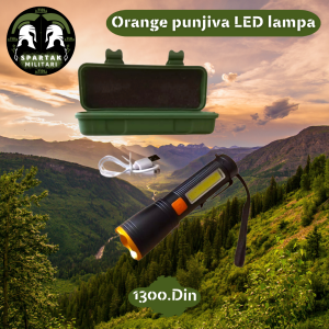 Orange punjiva LED lampa sa metalnim rubovima i kaišem, postavljena pod uglom.